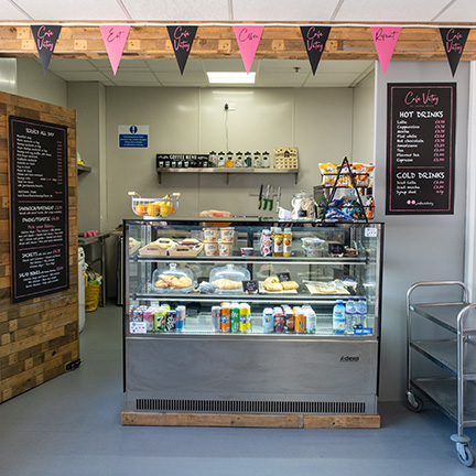 A wide angle image of the cafe in Victory centre, featuring a fridge with drinks and blackboards with menus