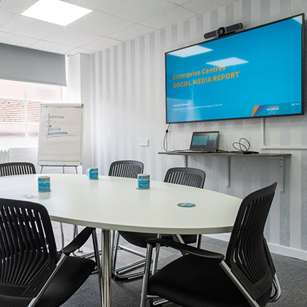 An empty office meeting room with a table and large TV monitor on the wall